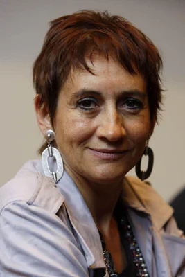 Caroline Loeb, portrait rapproché aux cheveux rouge-brun et grandes boucles d'oreilles.