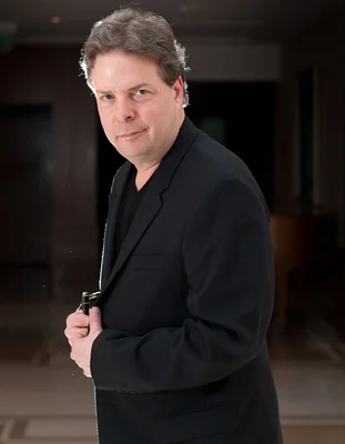 Douglas Kennedy, répondant aux questions des lecteurs d'Elle, veste noire, sourire en coin.
