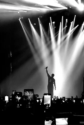 Damso en concert, silhouette dramatique sous les projecteurs, foule en contrebas.