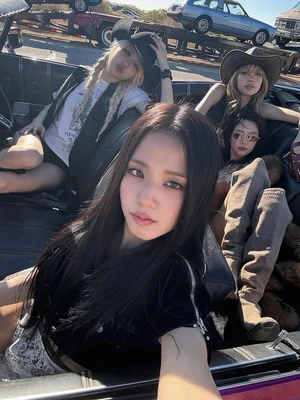 Blackpink dans une voiture décapotable, une membre prenant un selfie, les autres en chapeaux de cowboy.