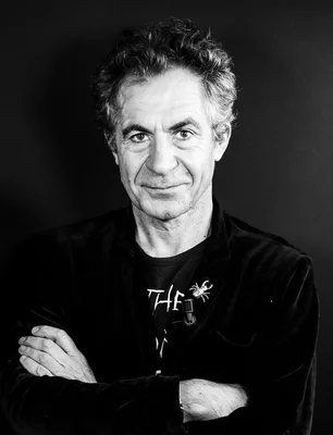Étienne Klein, portrait en noir et blanc, bras croisés, avec une épingle scorpion au revers.