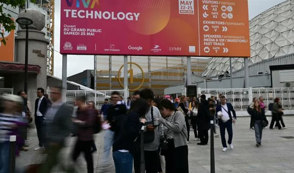 Attroupement devant la banderole 'VIVA TECHNOLOGY' à l'entrée extérieure du salon, dans un cadre urbain moderne.