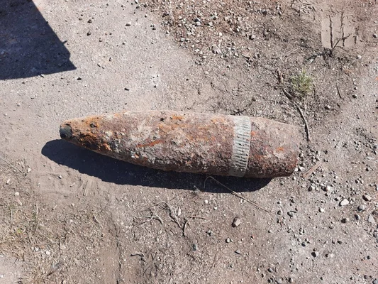 Obus rouillé de la Seconde Guerre mondiale découvert sur un sol graveleux.
