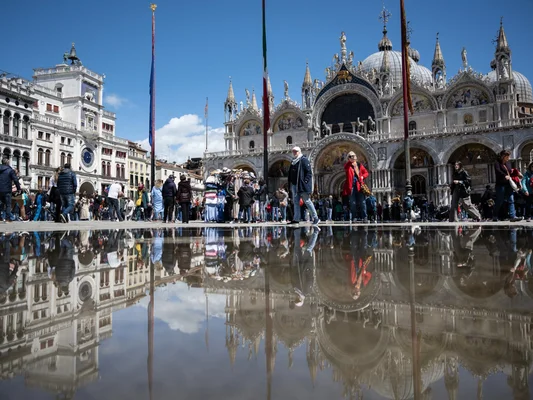 La place Saint-Marc et la basilique Saint-Marc reflétées dans une flaque d'eau à Venise.