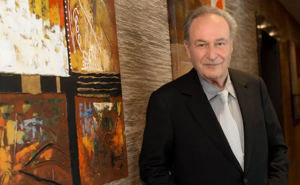 Gérard Brémond devant une œuvre d'art abstraite.