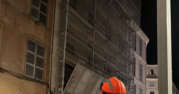 Immeuble sous échafaudages et filets de protection, de nuit.