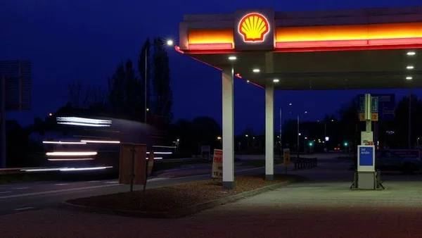 Station-service Shell de nuit, avec des traînées lumineuses de voitures.