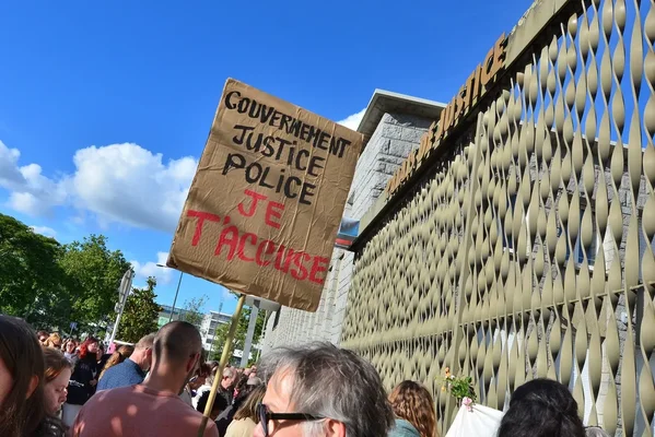 Manifestation avec une pancarte accusant le gouvernement, la justice et la police.