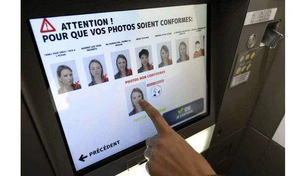 Écran d'une borne photo automatique présentant des exemples de photos d'identité valides et invalides, un rappel des normes strictes pour les documents officiels.