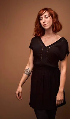 Pénélope Bagieu en studio, robe noire et tatouage de couronne.