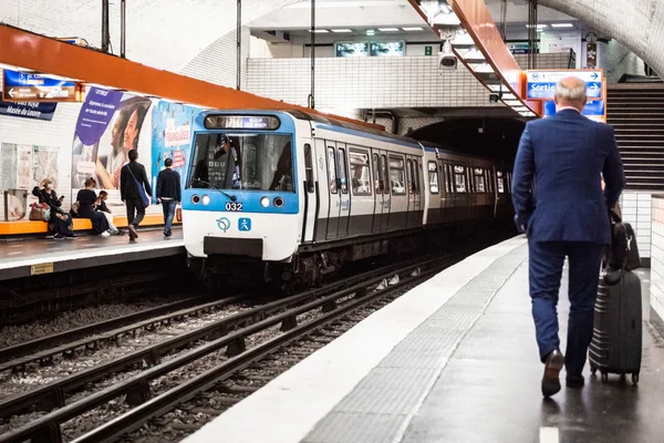 Un métro MF 67 arrive en station, des voyageurs sur le quai.