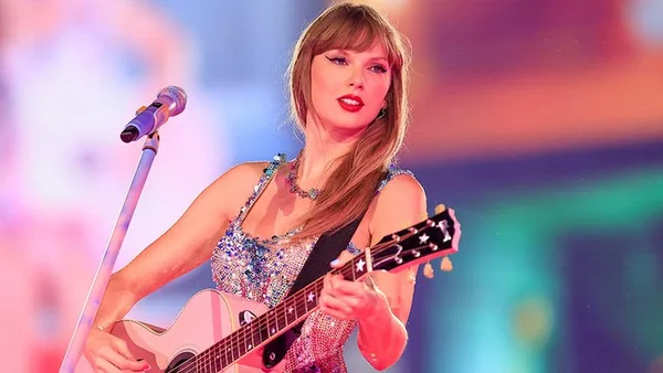 Taylor Swift interprète un morceau sur scène avec sa guitare acoustique.