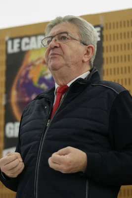 Jean-Luc Mélenchon présente l'air du peuple, poings serrés, devant une banderole.