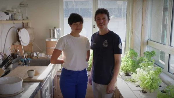 Un couple dans la cuisine de l'appartement du futur, avec un jardin hydroponique intérieur.