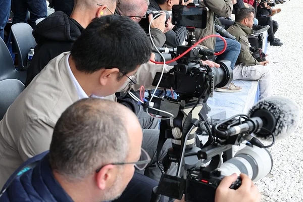Photographes et vidéastes de presse munis d'équipements professionnels lors d'un événement, symbolisant l'accréditation des journalistes.