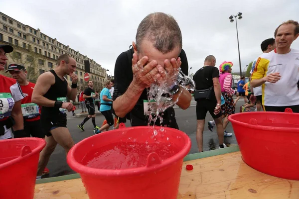Un athlète se rafraîchissant à un point d'eau lors d'une course par temps caniculaire, une image des défis posés par la chaleur.