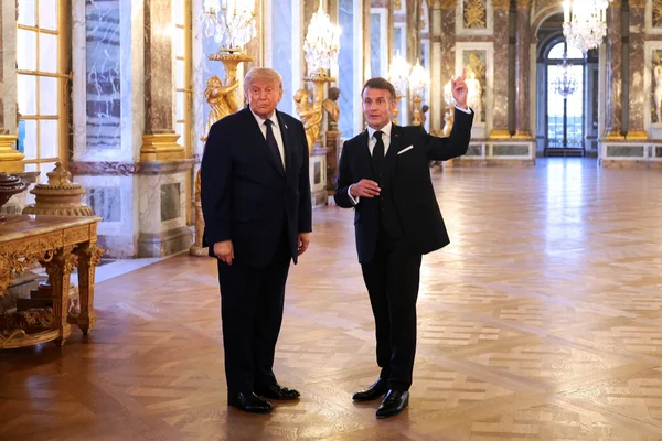 Discussion entre deux invités dans le cadre majestueux du château de Versailles.