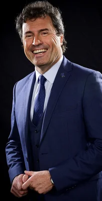 Portrait d'Omar da Fonseca en costume bleu, souriant devant un fond noir.