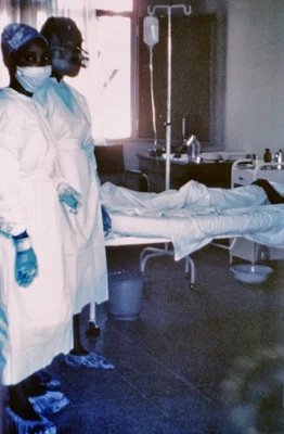 Cette photographie de 1976 montre deux infirmières debout devant le cas d'Ebola numéro 3, qui a été traité, puis est décédé à l'hôpital Ngaliema, à Kinshasa, au Zaïre. La fièvre hémorragique Ebola (Ebola HF) est une maladie grave, souvent mortelle chez les humains, les chimpanzés, les gorilles et les orangs-outans, qui est apparue sporadiquement depuis sa première identification en 1976.