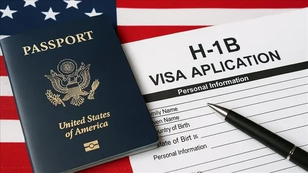 Passeport américain et formulaire de demande de visa H-1B sur un drapeau américain.