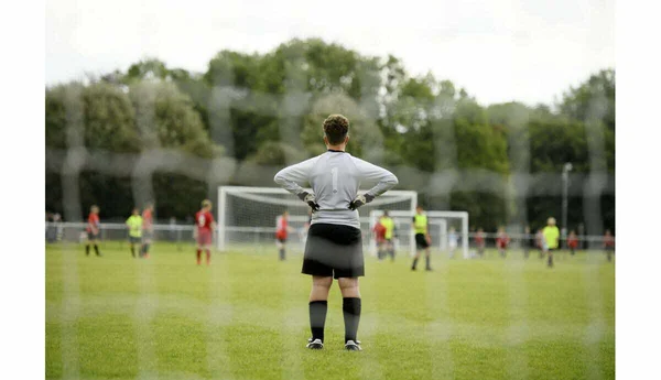 Vue d'un gardien de but sur un terrain de football, illustrant l'ambiance d'un match.