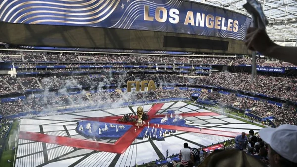 Annonce des villes hôtes : Los Angeles célébrée avec une banderole et un trophée sur le terrain.