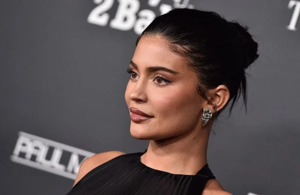 Kylie Jenner en robe noire et boucles d'oreilles diamant, coiffée en chignon.