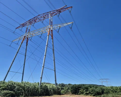Pylône électrique multi-circuits dans un paysage rural.