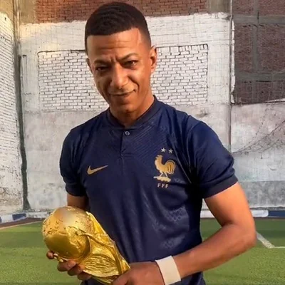 Le sosie égyptien de Kylian Mbappé, en maillot de l'équipe de France, désignant l'écusson du coq sur sa poitrine.