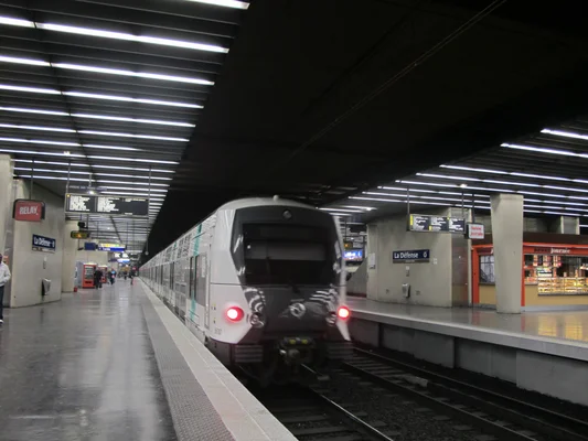 Un RER A arrivant à la station La Défense, avec des voyageurs sur le quai.