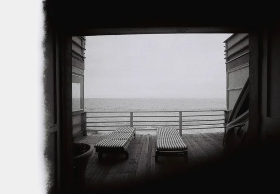 Vue depuis l'intérieur vers l'océan, avec deux chaises longues sur le pont, photographiée par Elisa Routa.