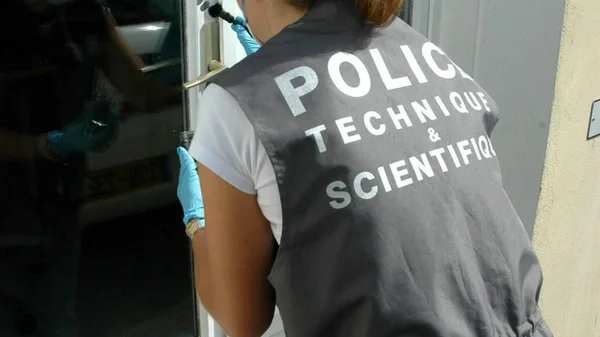 Enquêteur de la police technique et scientifique relevant des empreintes sur une porte à Nantes, après la découverte d'une balle perdue dans une cuisine.
