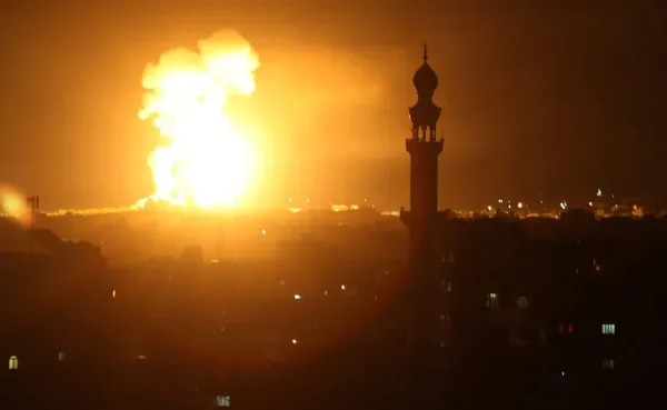 Explosion illuminant le ciel nocturne, symbolisant les frappes en réponse aux tirs de roquettes.