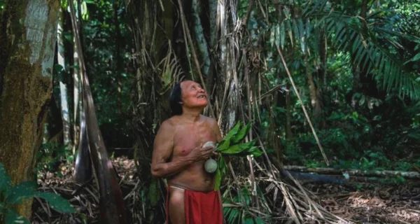Un homme indigène en interaction avec la forêt amazonienne, illustrant le lien entre l'homme et la nature.