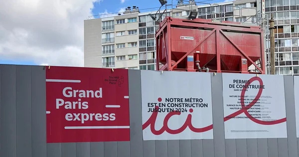 Palissade de chantier du Grand Paris Express avec affiches promotionnelles.