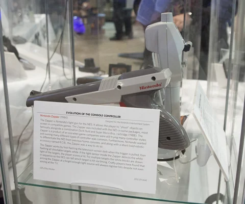 Le Zapper de la NES exposé dans un musée, avec un panneau retraçant l'évolution des manettes de jeu.
