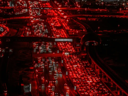 Un échangeur autoroutier engorgé la nuit, illustrant la densité du trafic et la circulation des véhicules.