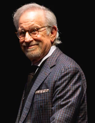 Steven Spielberg souriant en veste à carreaux.