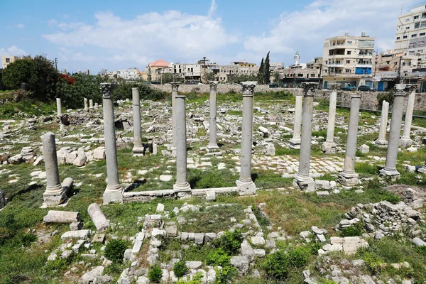 Les ruines romaines de Tyr, site classé à l'UNESCO, avec des colonnes antiques et la ville moderne en arrière-plan.