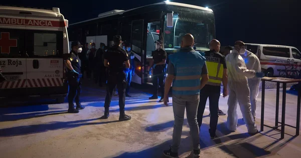 Intervention de secouristes et de policiers autour d'un bus et d'une ambulance de la Croix-Rouge lors d'une opération nocturne liée à l'immigration.