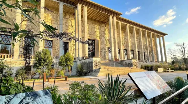 Le Palais de la Porte Dorée vu depuis le jardin, écrin de l'exposition gratuite « Aux origines ».