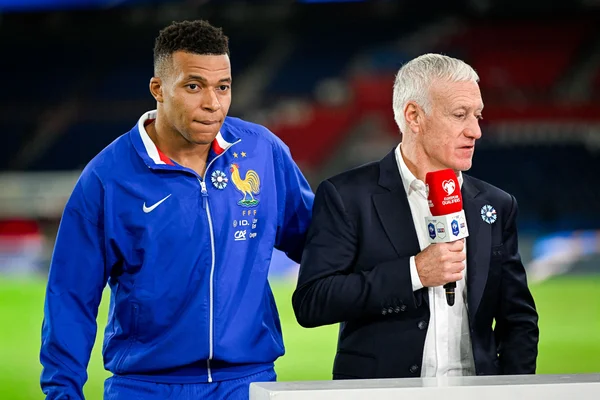 Didier Deschamps, sélectionneur des Bleus, échange avec un officiel sur le terrain.