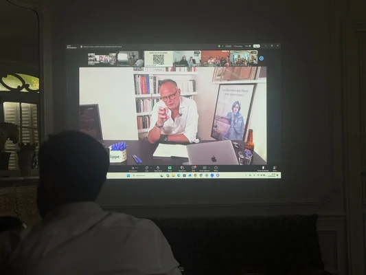 Un participant regarde la visioconférence d'Édouard Philippe projetée sur un grand écran.