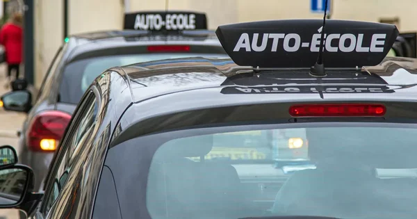 Deux voitures argentées avec panneaux 'AUTO-ÉCOLE' alignées, vue arrière.