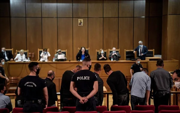 Les accusés d'Aube Dorée devant le tribunal, encadrés par la police.