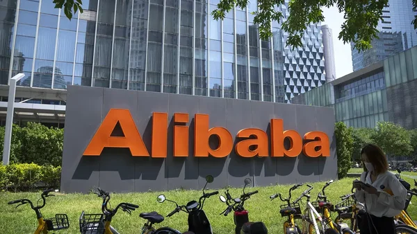Panneau du siège social d'Alibaba à Hangzhou, avec des vélos en libre-service et une employée au téléphone.