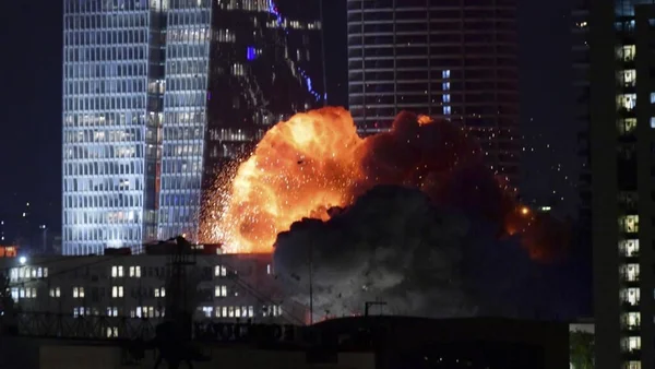 Explosion massive lors d'une frappe nocturne en Iran, avec des étincelles et une boule de feu.