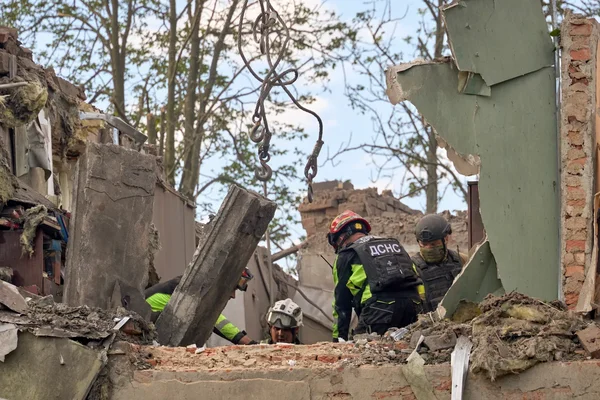 Des secouristes ukrainiens fouillent les décombres d'un immeuble effondré.