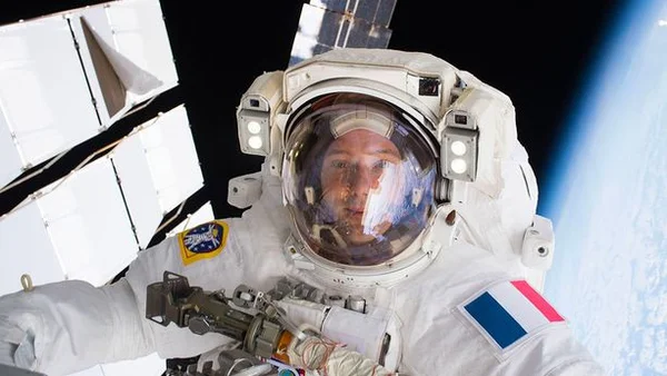 Astronaute en sortie extravéhiculaire, avec la Terre en arrière-plan.