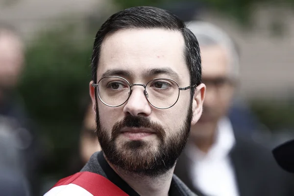 Gros plan de David Guiraud, député, arborant une écharpe rouge.
